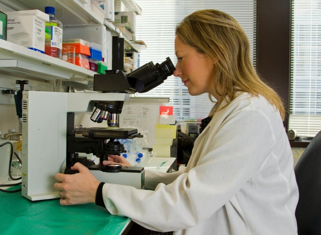 Mujer usando un microscopio en laboratorio
